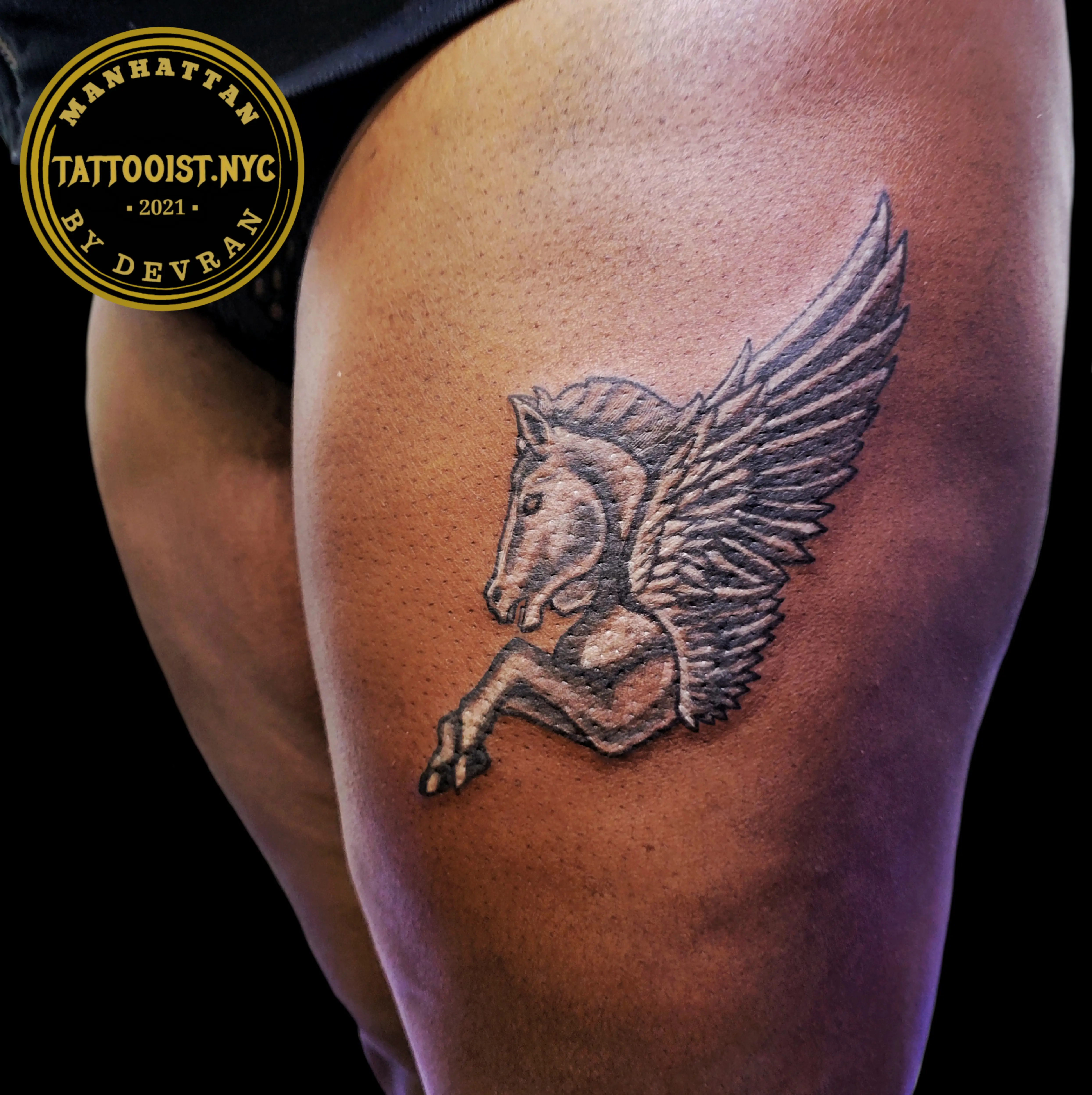 Tattoo of Pegasus with detailed wings in black and gray on the thigh.