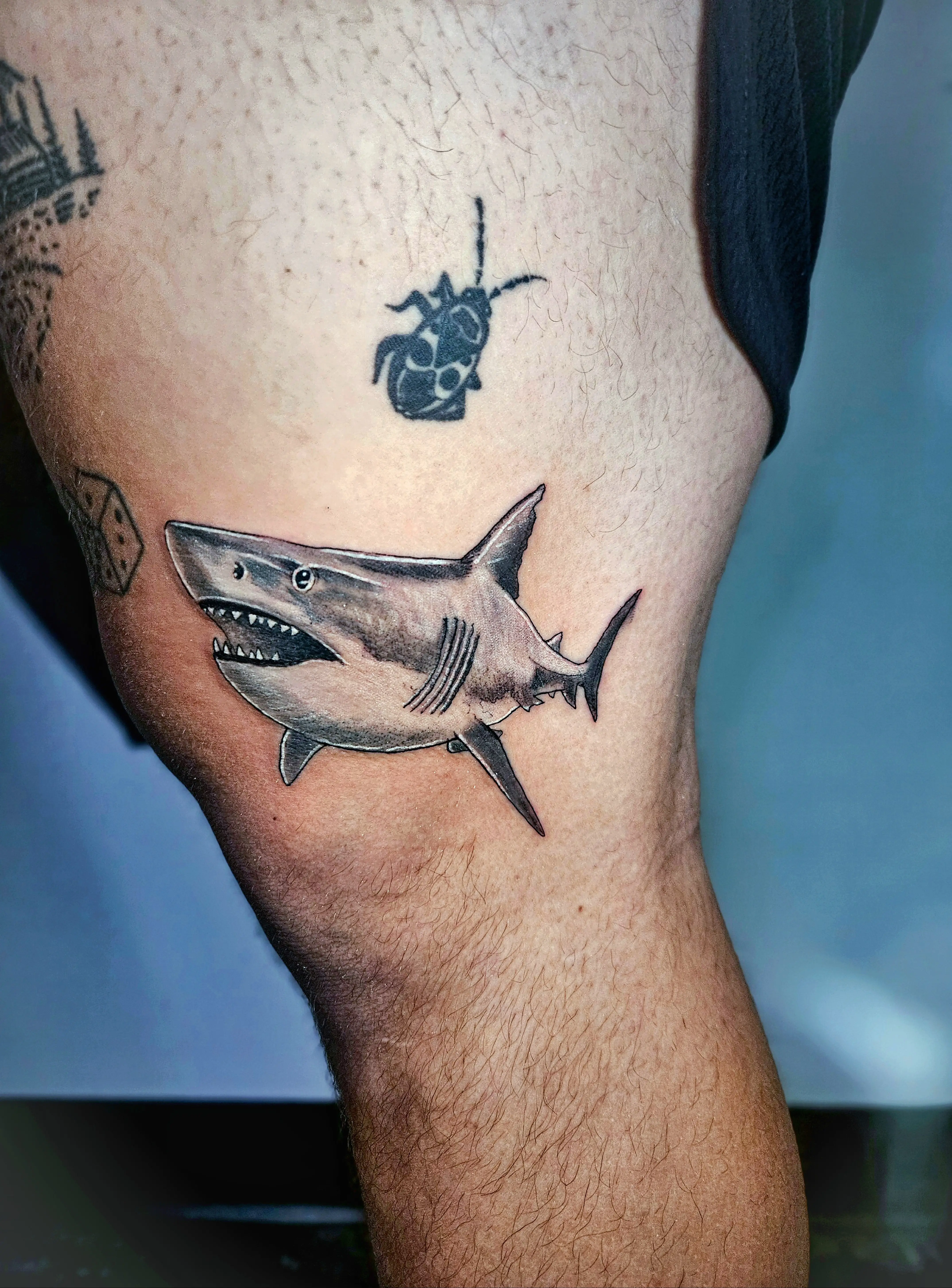 Realistic great white shark tattoo on the thigh in black and gray.